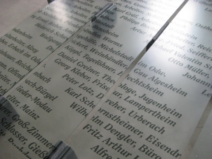 Namen einiger Häftlinge auf der gläsernen Gedenktafel